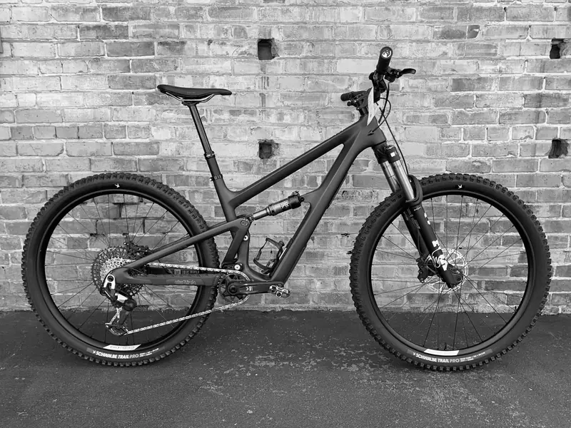 Full-suspension mountain bike against a brick wall