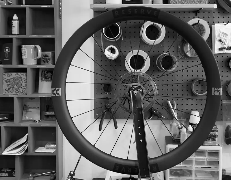 Carbon wheel in a truing stand in front of the parts wall